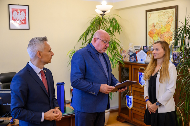 Starosta wraz z członkiem zarządu wręczają nagrodę Sylwii