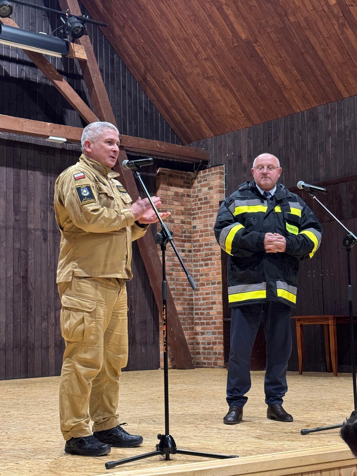 Przedstawiciel służby przemawia, obok starosta